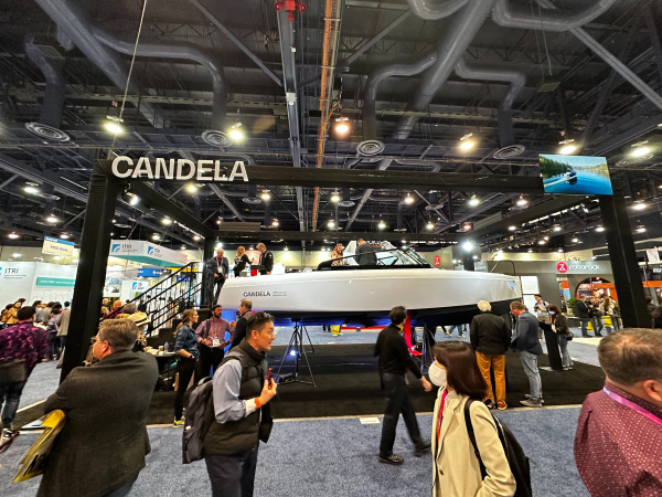 A white Candela C-8 boat on display at CES 2023, with attendees in the foreground and background