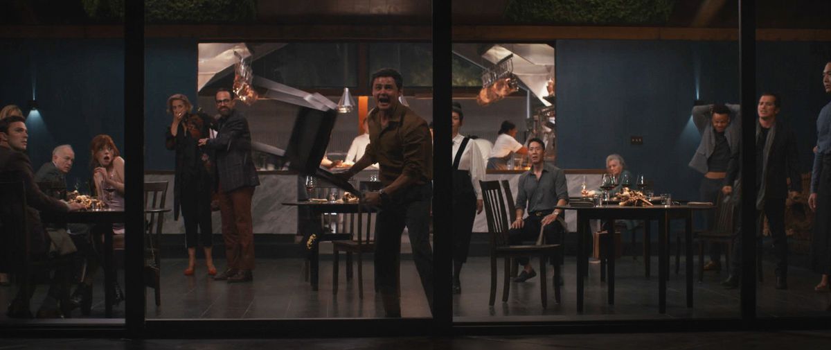 Un uomo frenetico fa oscillare una sedia contro una delle pareti di vetro in un ristorante di lusso nel tentativo di frantumarlo e scappare, mentre il resto degli avventori spaventati guarda in una scena di The Menu