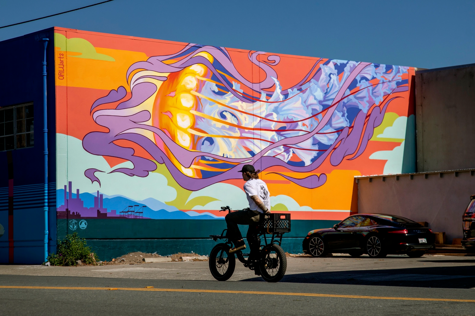 Seorang pengendara sepeda melintas di depan mural raksasa berwarna-warni yang menggambarkan ubur-ubur
