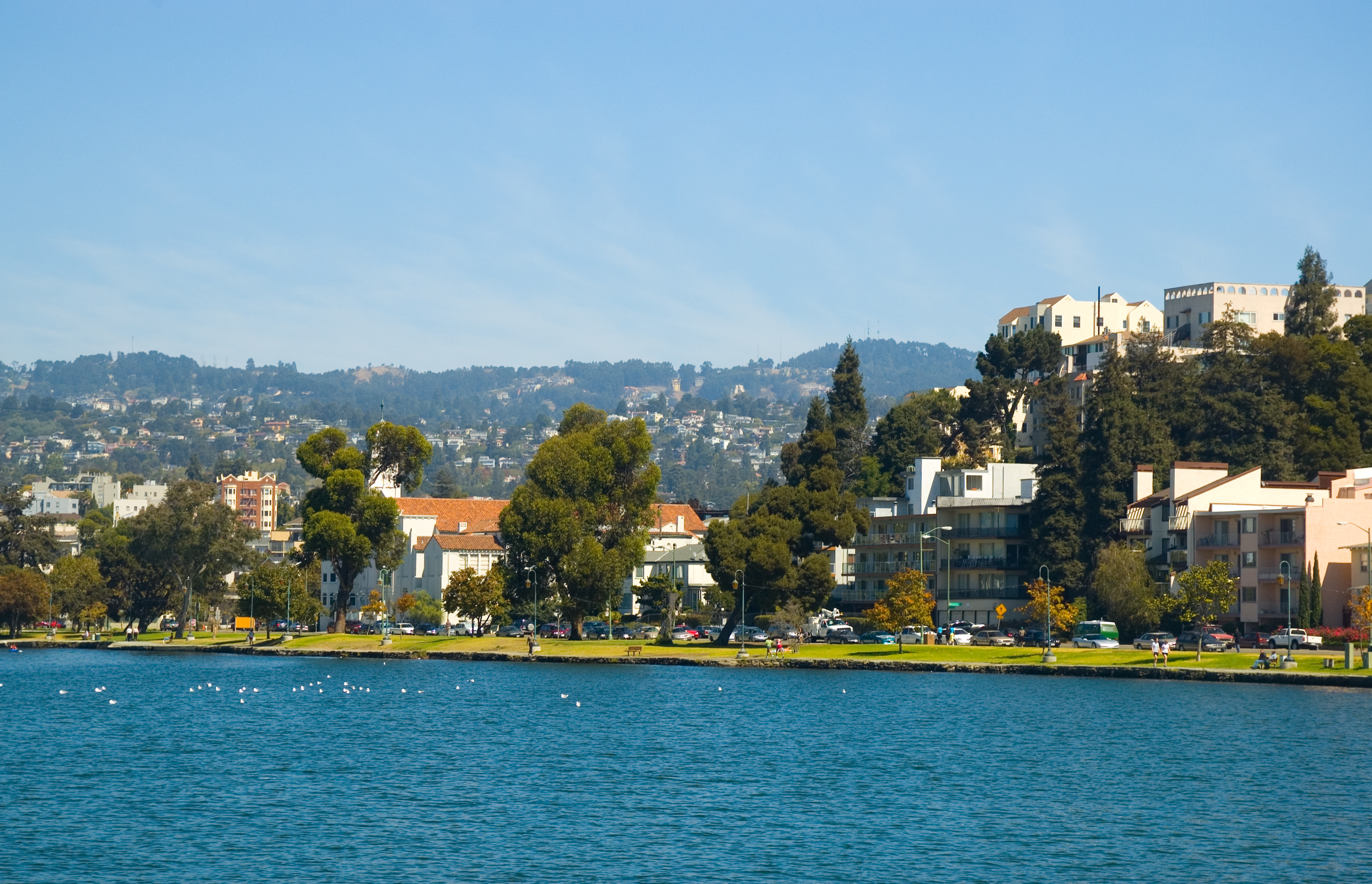 Lake Merritt, park, apartment buildings, trees, and the Oakland Hills in the background