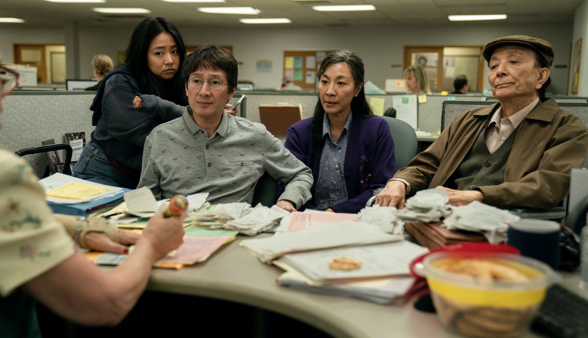 The main cast of Everything Everywhere All at Once sits together at an IRS hearing