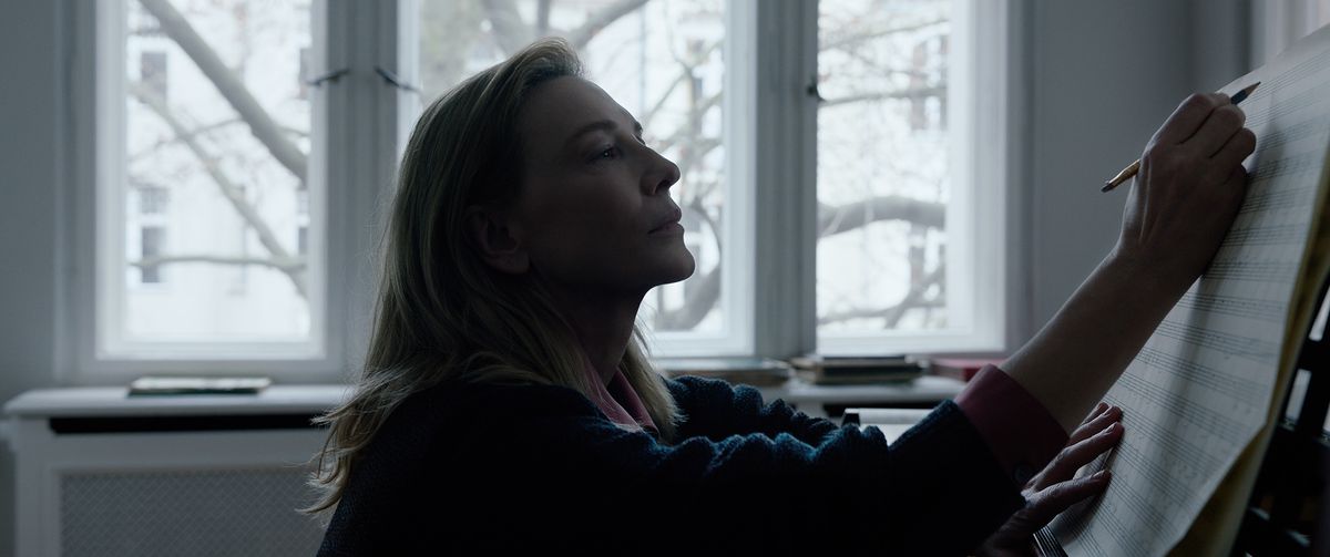 Lydia Tár (Cate Blanchett) composing at her piano in a dimly lit room in Todd Field’s Tár