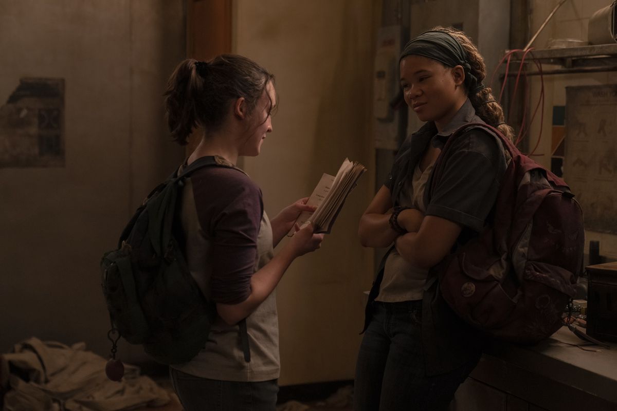 Ellie (Bella Ramsey) reads No Pun Intended: Volume Too to Riley (Storm Reid) who’s listening with her arms folded