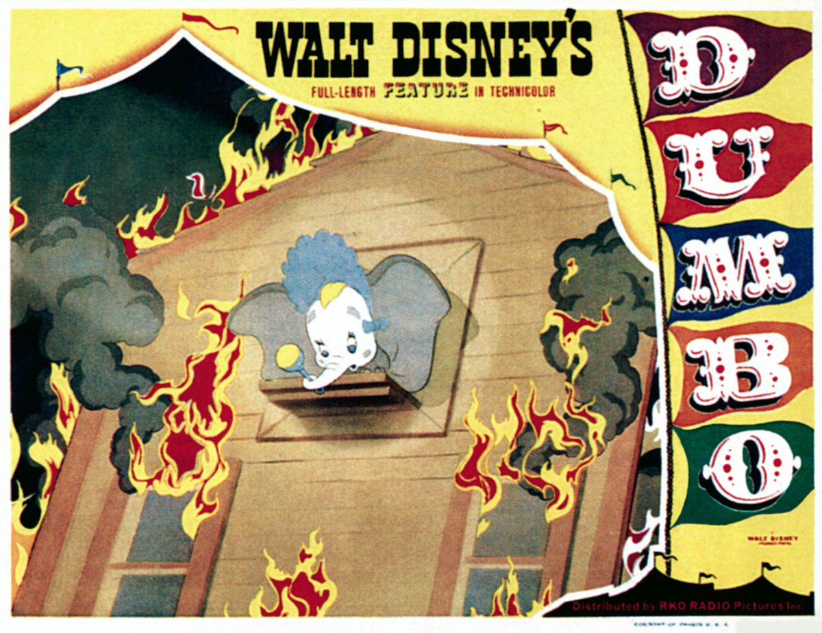 A 1941 lobby card from Walt Disney’s Dumbo, with the titular big-eared elephant in clown makeup and a baby’s bonnet, looking out of the window of a burning house, bordered by the film’s title treatment and the open flap of a circus tent