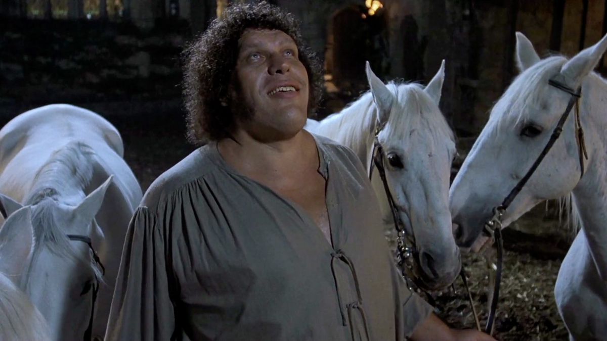 Andre the Giant smiles at the sky while standing next to white horses in The Princess Bride.