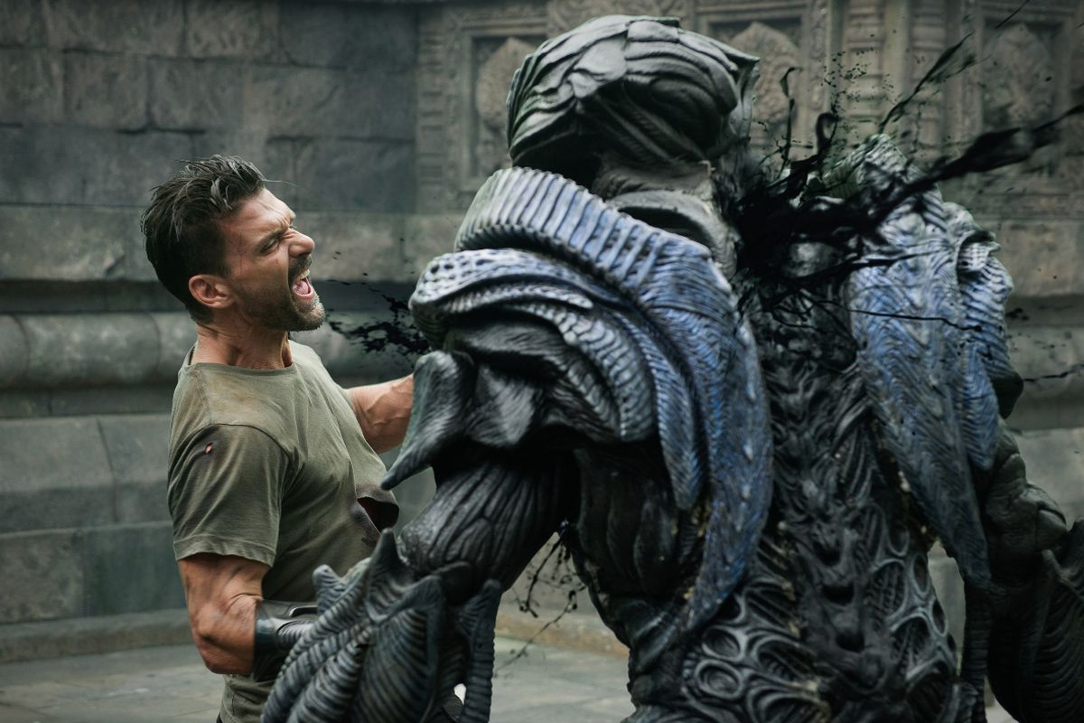 Frank Grillo as Mark Corley in Beyond Skyline, killing a large, humanoid alien. The alien’s body is made of overlapping plates of organic armor.