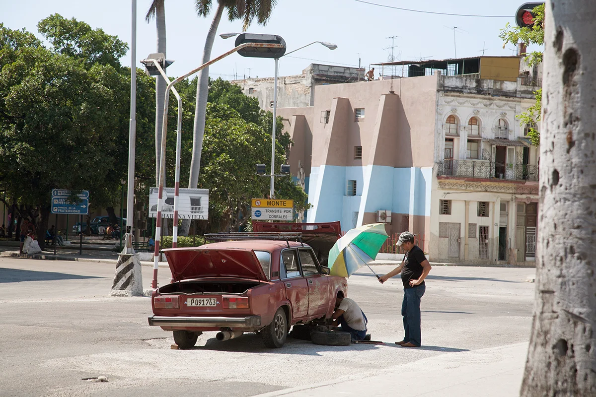 쿠바, 하바나에서 고장난 자동차에서 작업하는 동안 정비공이 음영 처리됩니다.
