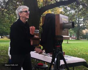 Artist Craig Murphy with wooden tintype camera and Glens Falls Art logo