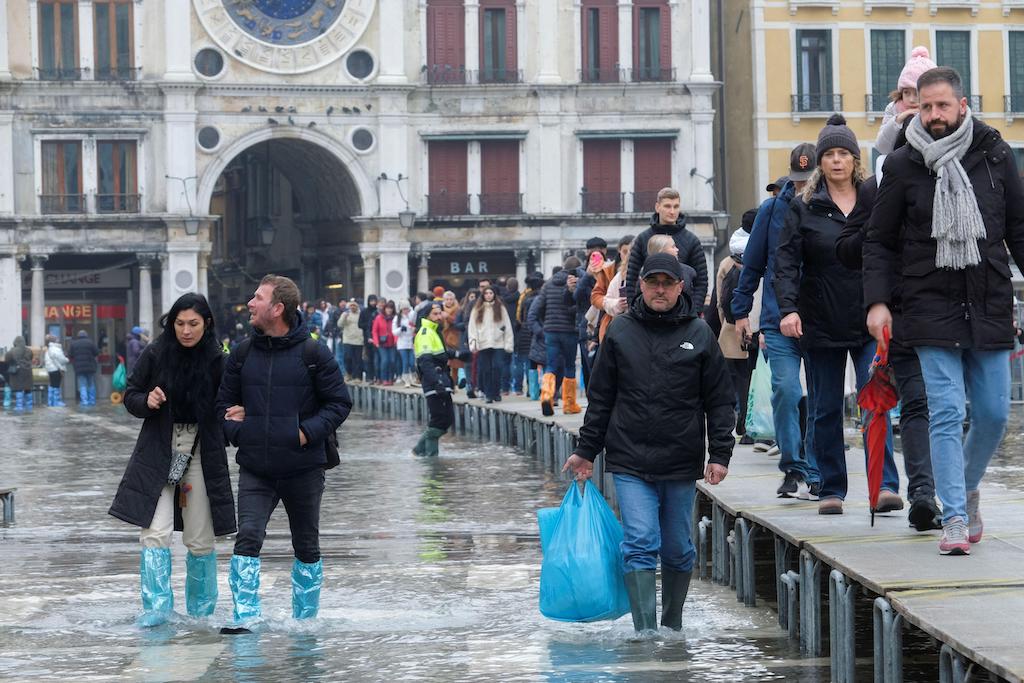 Ludzie brodzą w wodzie na zalanym placu św. Marka podczas sezonowej wysokiej wody w Wenecji, Włochy, 10 grudnia 2022 r.