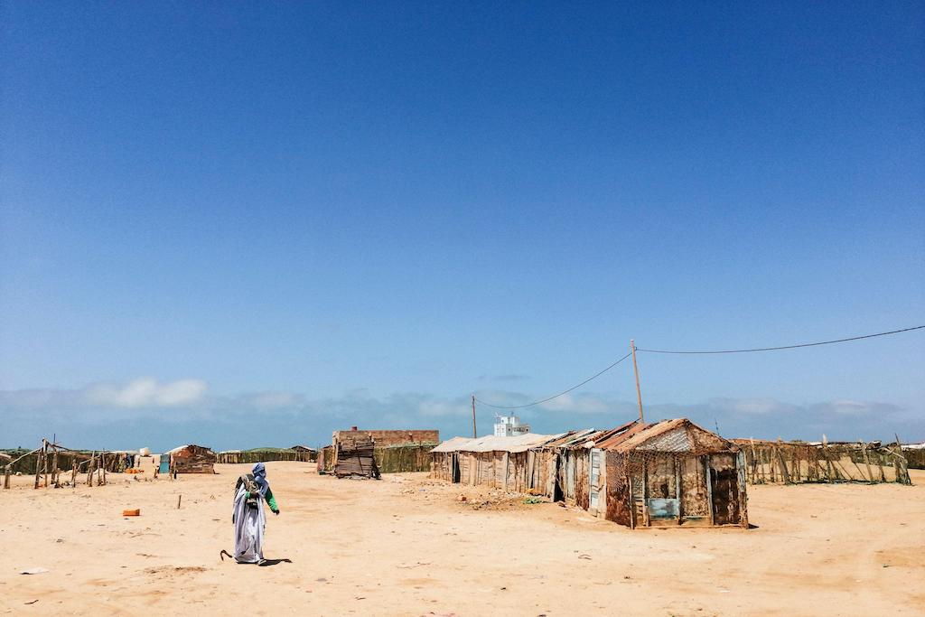 An individual is pictured alongside a row of huts in Banc d'Arguin National Park, Nouamghar, Mauritania. 