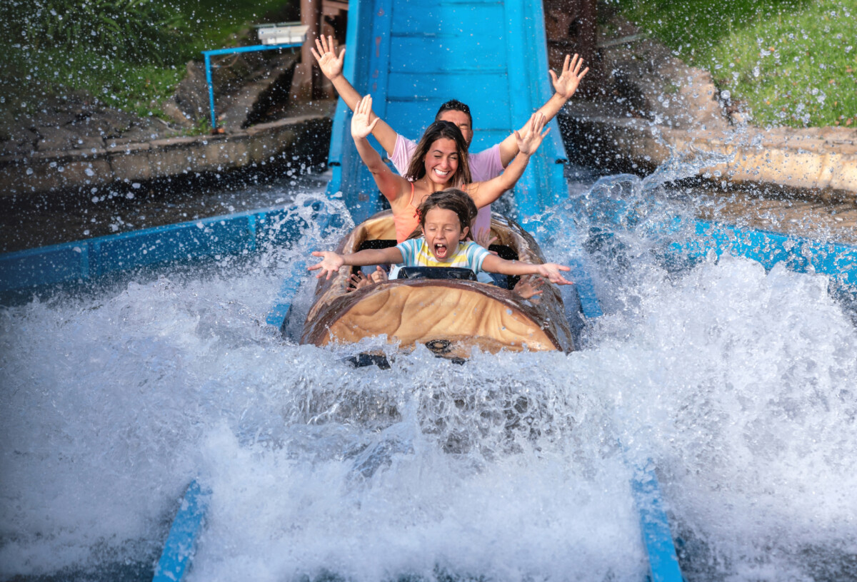 Happy family having fun in an amusement park riding on a fun water ride