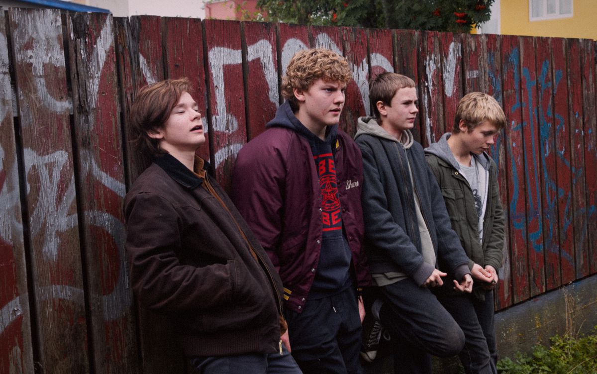 A group of young Nordic boys lean against a graffiti’d wall in Beautiful Beings.