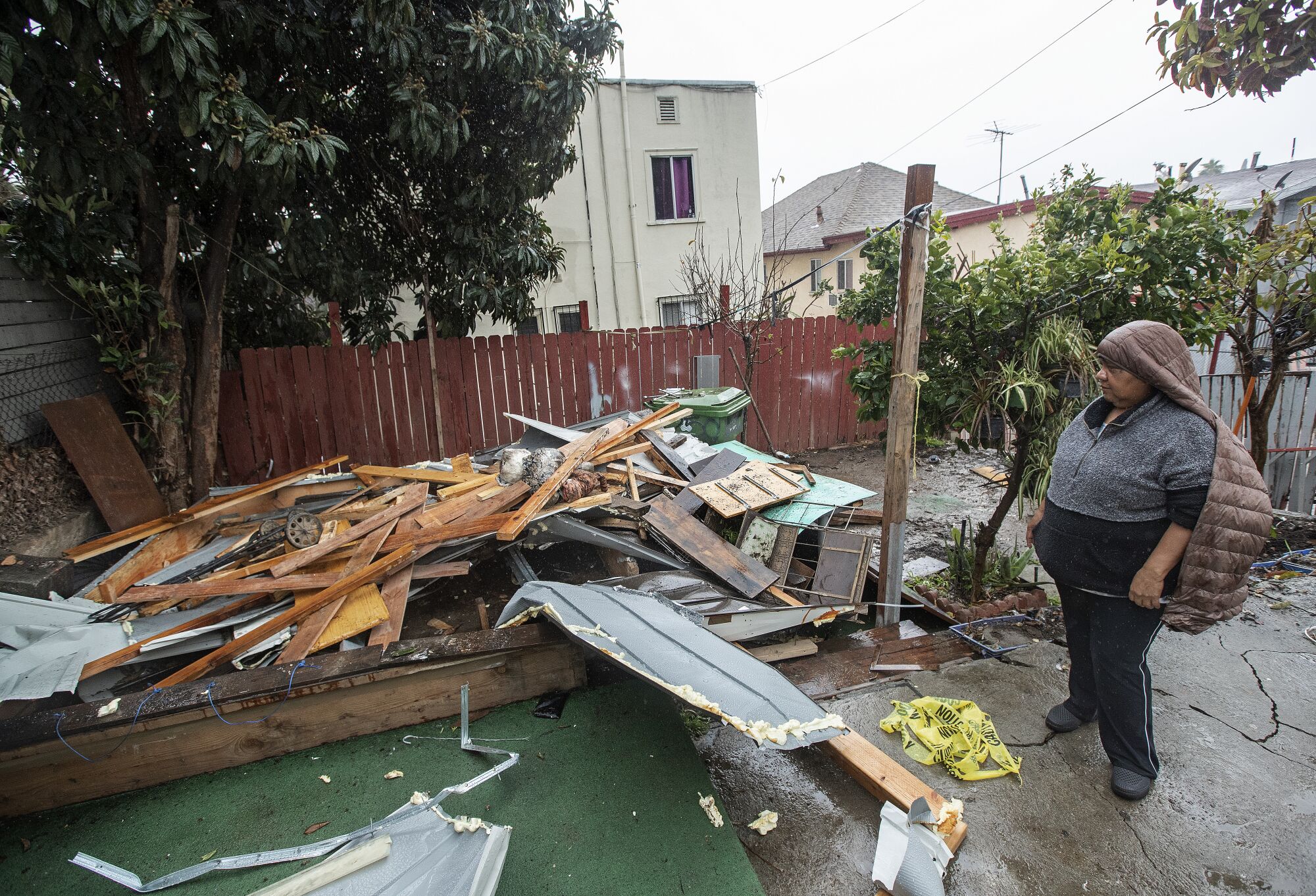 A woman looks at the shredded remains of her storage shed outside of her apartment.