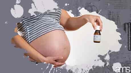 زن باردار یک بطری کوچک CBD در دست دارد
