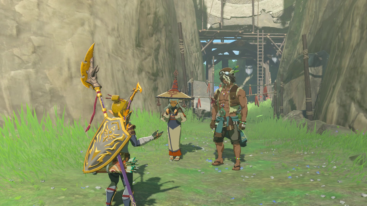 Link stands and talks to Paya and Tauro, two people standing by the Ring Ruins in Tears of the Kingdom. Paya is standing in robes and a large hat, whereas Tauro has his abs out.
