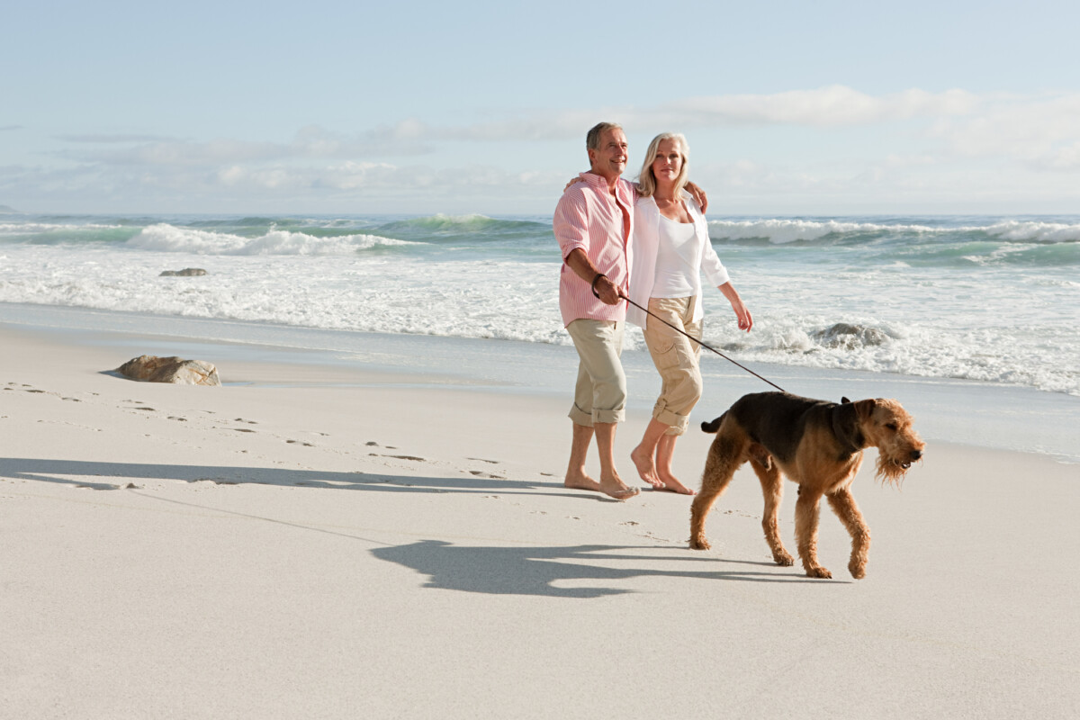 Par som går tur med hund ved sjøen