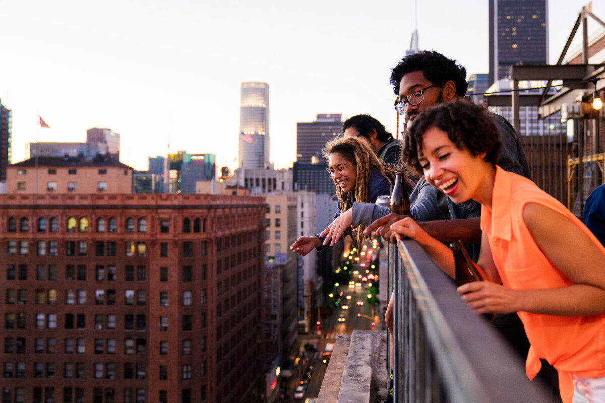 Groupe d'amis traînant ensemble sur un balcon du centre-ville de Los Angeles, regardant par-dessus la rue. Los Angeles _ Getty