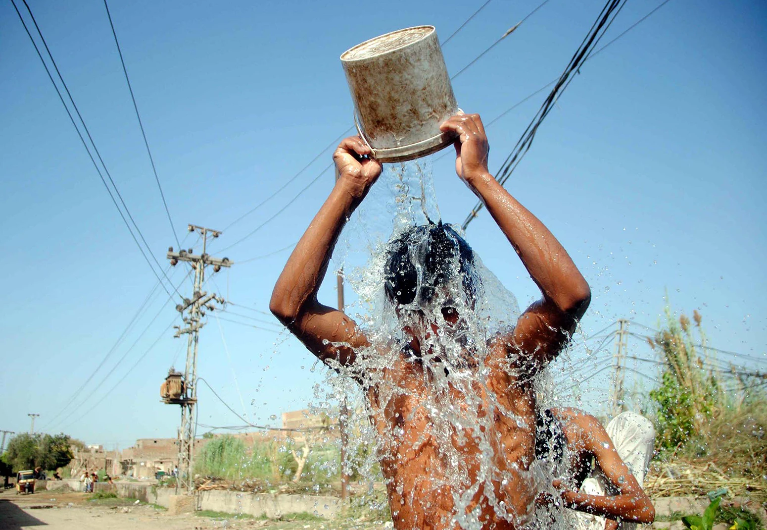 En ung mand hælder vand over sig selv under en hedebølge i Hyderabad, Pakistan, den 4. april 2022.