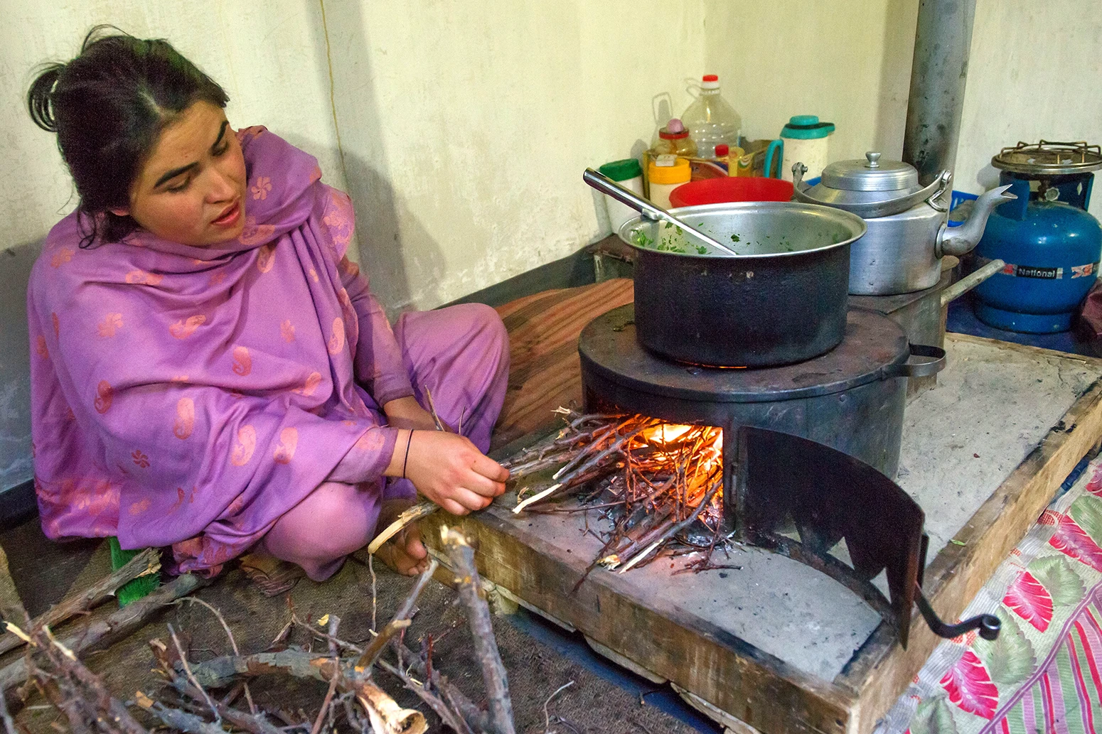Ženska kuha na ognju v svoji hiši v Gilgit-Baltistanu v Pakistanu.