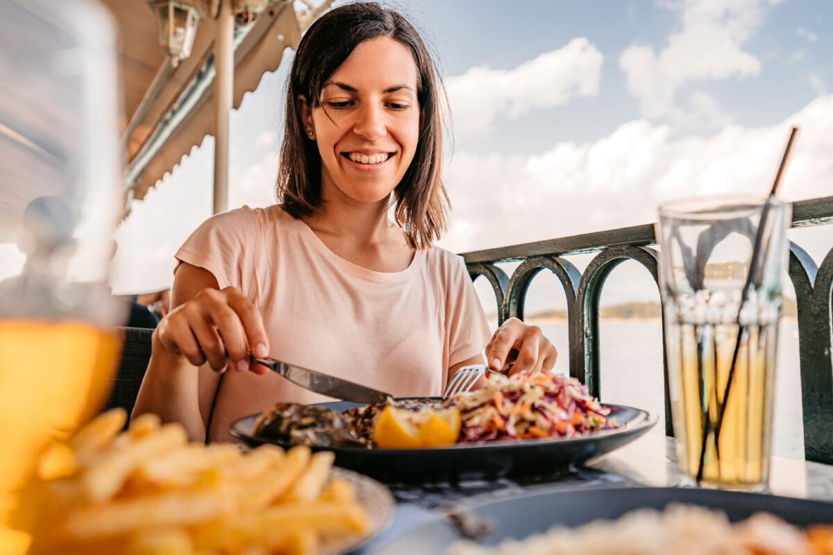 mujer disfrutando de una comida junto al mar.