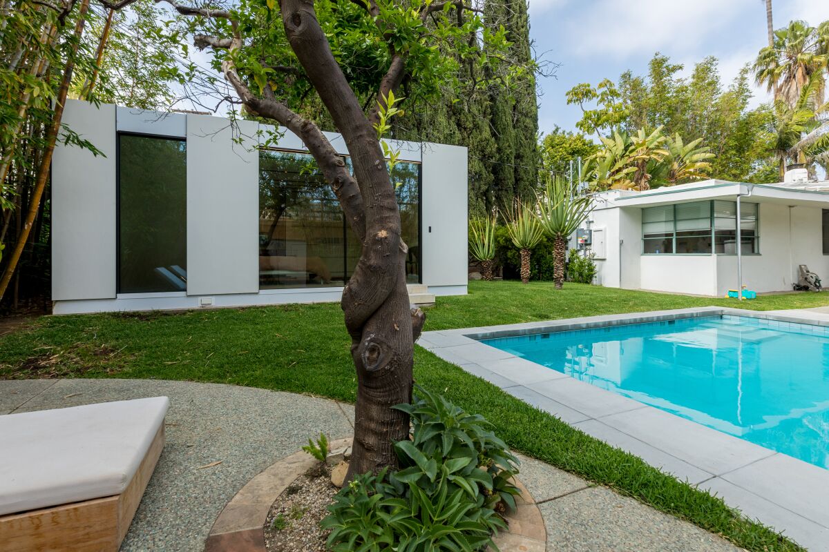 An ADU and a historic home sit side by side near a swimming pool.