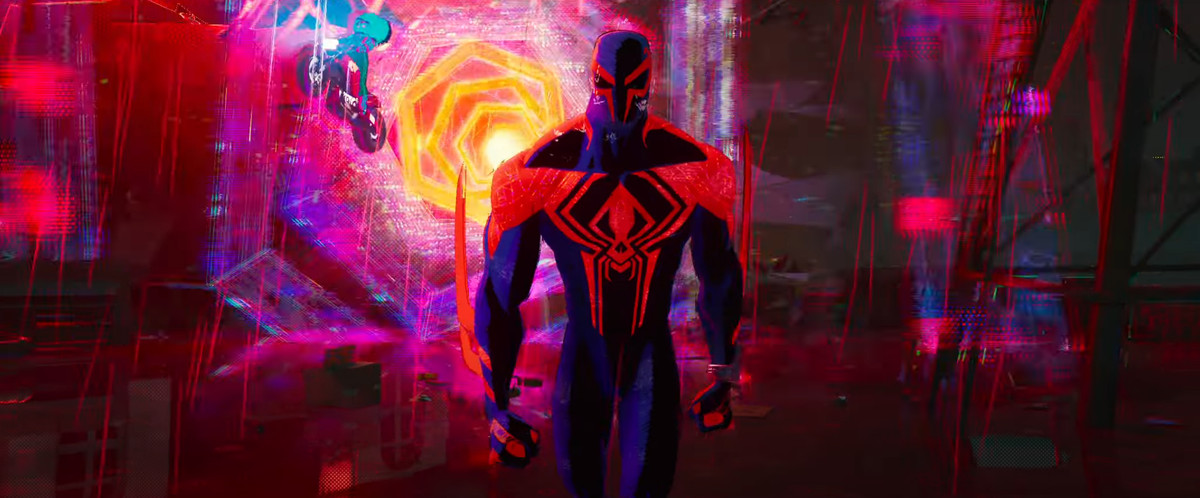Spider-Man 2099 walks toward the camera with a brightly colored wormhole of reds, pinks, yellows, and blues swirls behind him in Spider-Man: Across the Spider-Verse