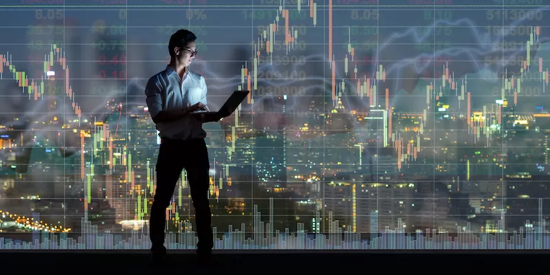 Asian businessman standing and using the smart mobile phone showing the Stock market chart over the cityscape background at night time, Business technology and trading concept