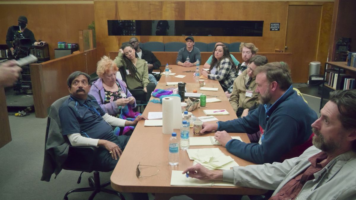 The cast of Jury Duty sitting at a table looking bored and frustrated