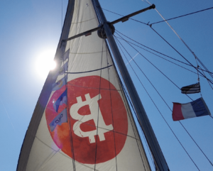 Bitcoin pluje po morjih: mornar na čolnu naslika velikan 'B' za promocijo kriptovalut čez ocean