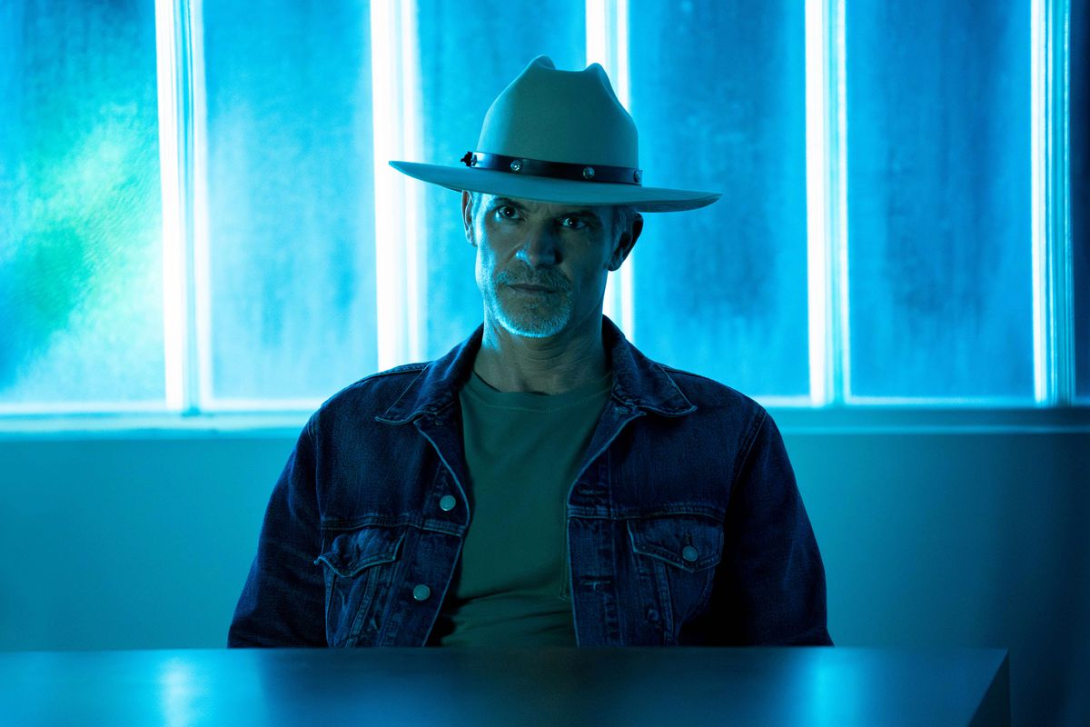 Raylan Givens (Timothy Olyphant) sitting in front of neon, looking pissy