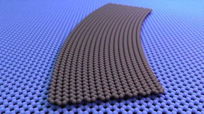 A curved graphene ribbon, illustrated in grey, shown laid flat against another graphene sheet. There is a continuous change in the twist angle between the ribbon above and the sheet below. In some places the atomic lattices of the two sheets line up at a 0° angle to each other, while in others, they are twisted relative to each other by as much as 5°. CREDIT
Cory Dean, Columbia University