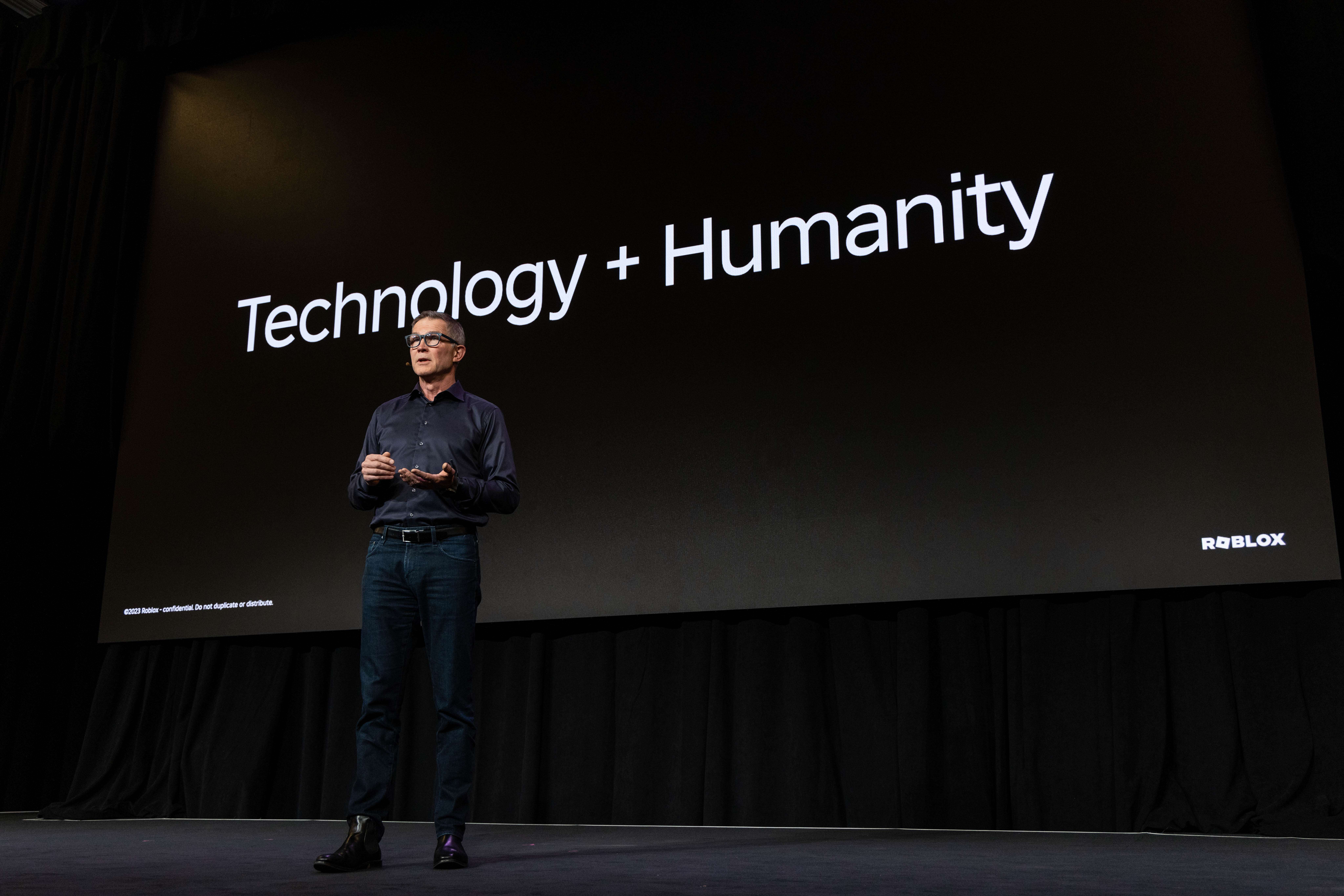 大卫站在舞台上，面前是一张写着“科技+人文”的幻灯片