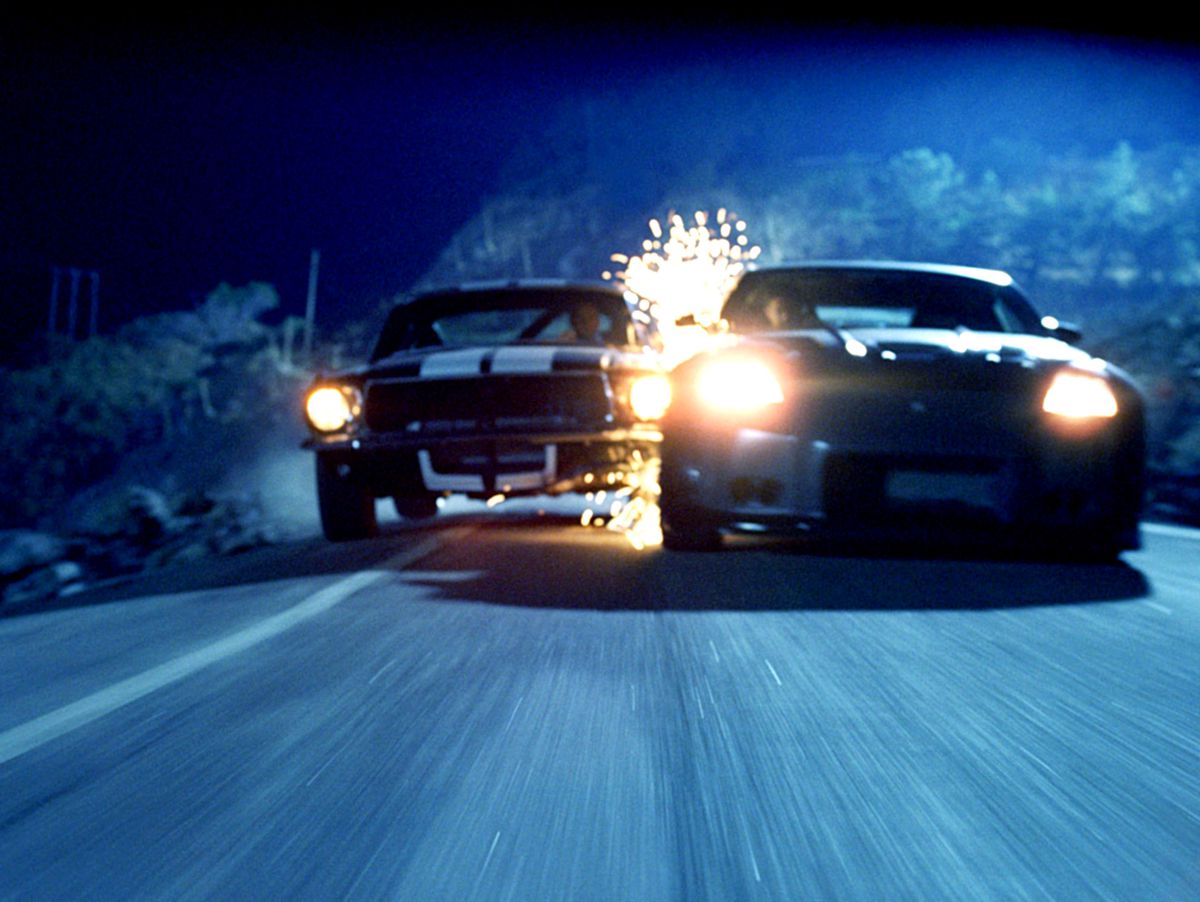 Sparks fly as two muscle cars collide while drifting on a narrow road in The Fast and the Furious: Tokyo Drift.