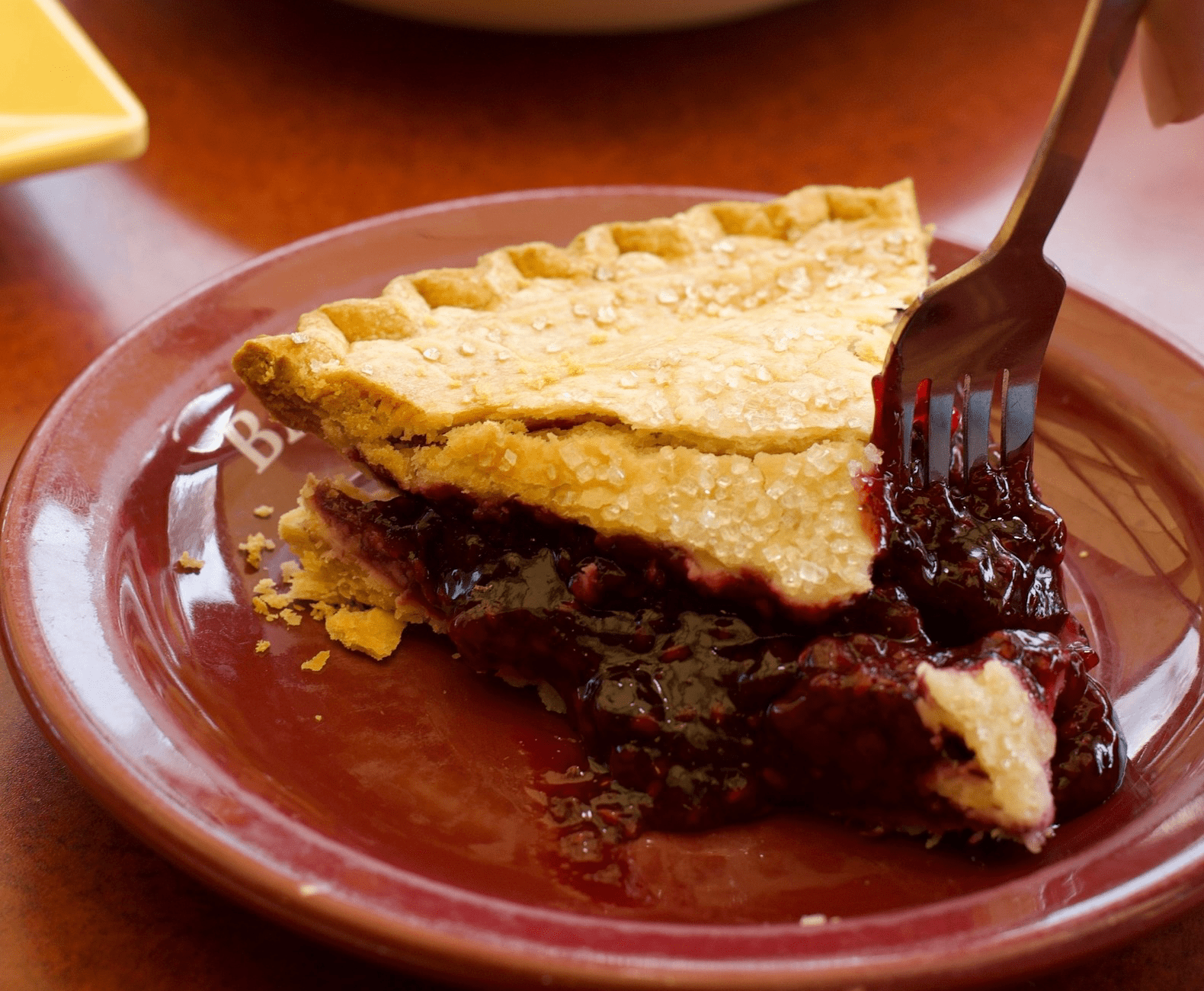 fork cutting a slice of blackberry pie - Bakers Square's signature dishes