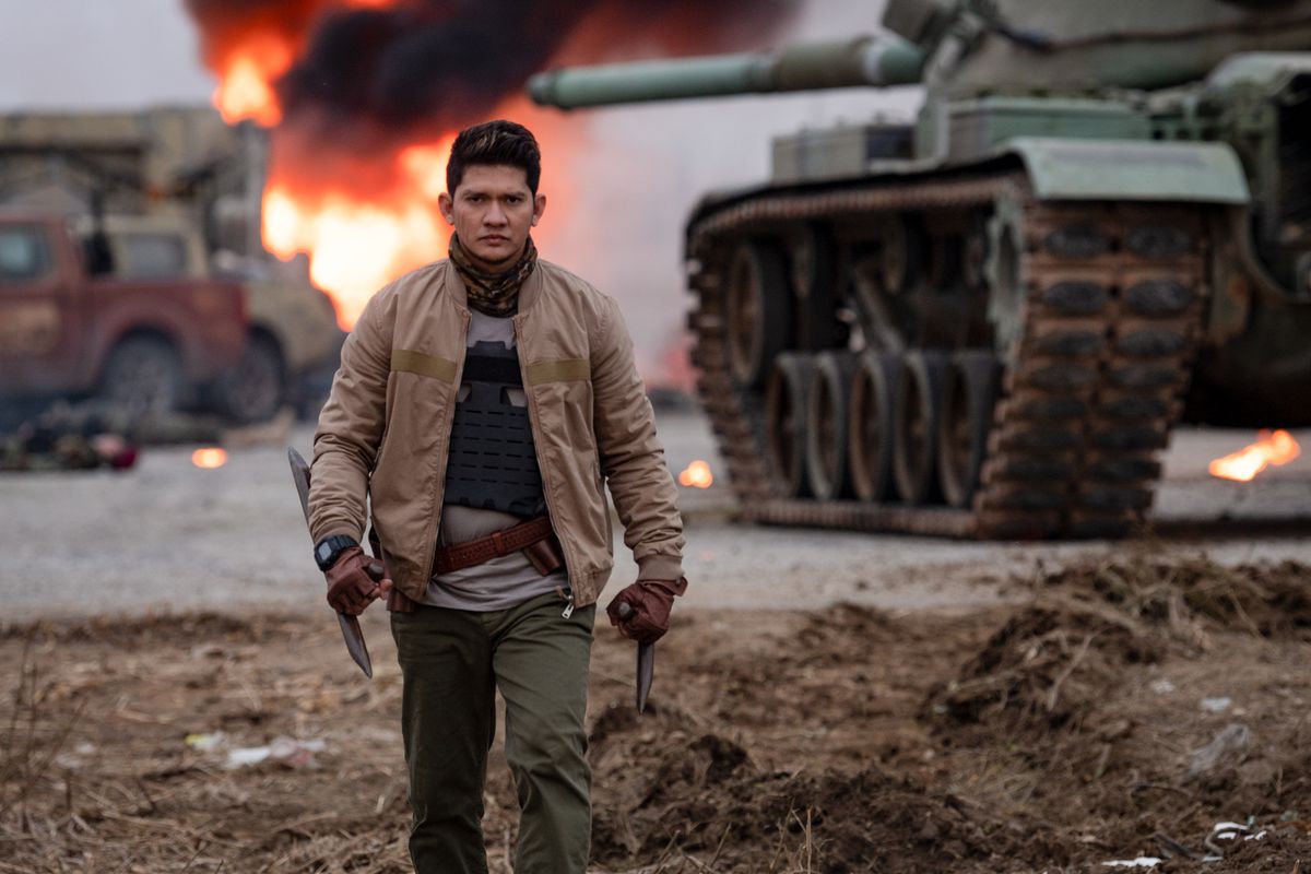 Iko Uwais as Rahmat, Expend4bles villain, walking away from an explosion with spiked tonfa in his hands and a tank just behind him. It’s very cool.