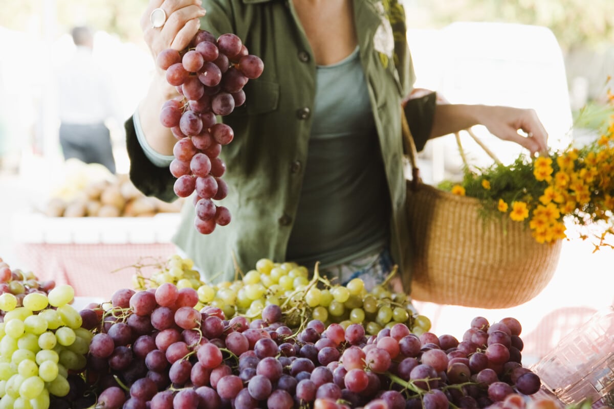 Frau mit Weintrauben auf dem Bauernmarkt