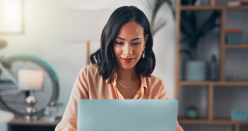 Woman working on laptop online, checking emails and planning on the internet while sitting in an office alone at work. Business woman, corporate professional or manager doing financial planning & budgeting.