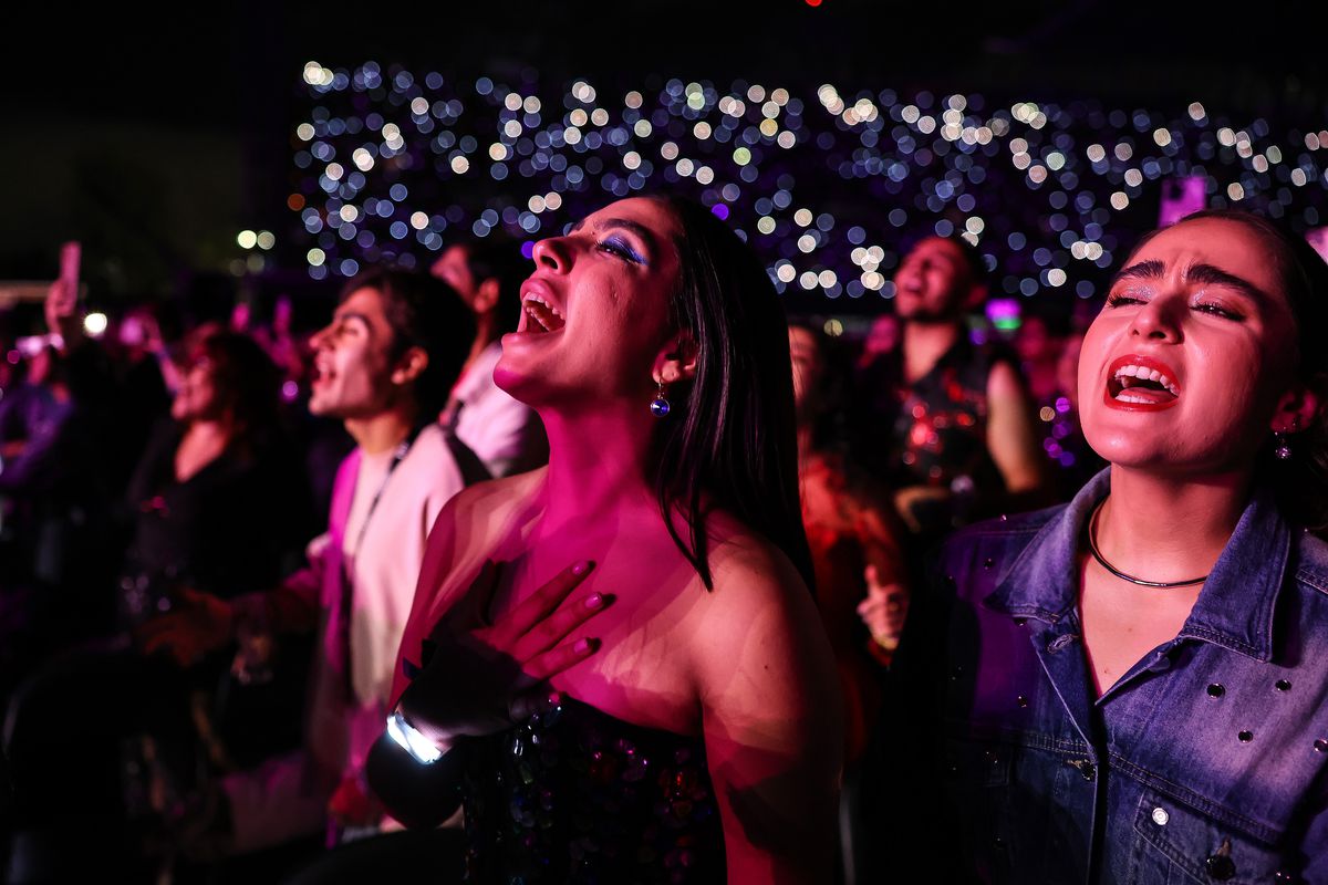 Fans at the Taylor Swift Eras Tour concert in Mexico, hands over their hearts, singing along to the music.