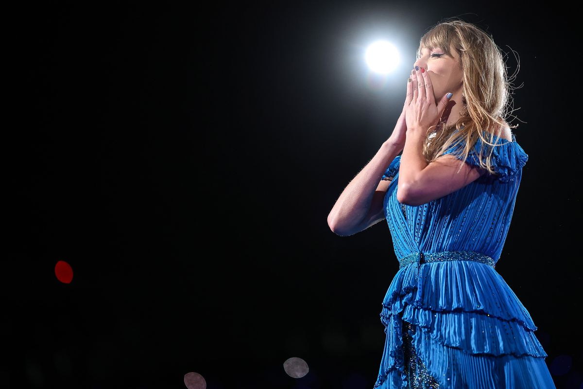 Taylor Swift performing in Mexico City as part of her Eras tour. She’s wearing a blue dress and air kissing the audience.