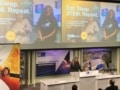 Анн-Мари Имафидон выступает на Эпплтонской космической конференции под экраном, на котором показаны фотографии улыбающихся молодых женщин и слова «Ешь. Спи. STEM. Повтори».