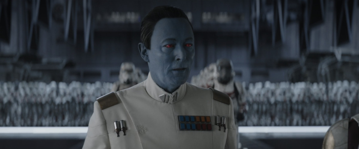 Lars Mikkelsen as Grand Admiral Thrawn, in full uniform and standing in front of rows and rows of stormtroopers in Ahsoka. 