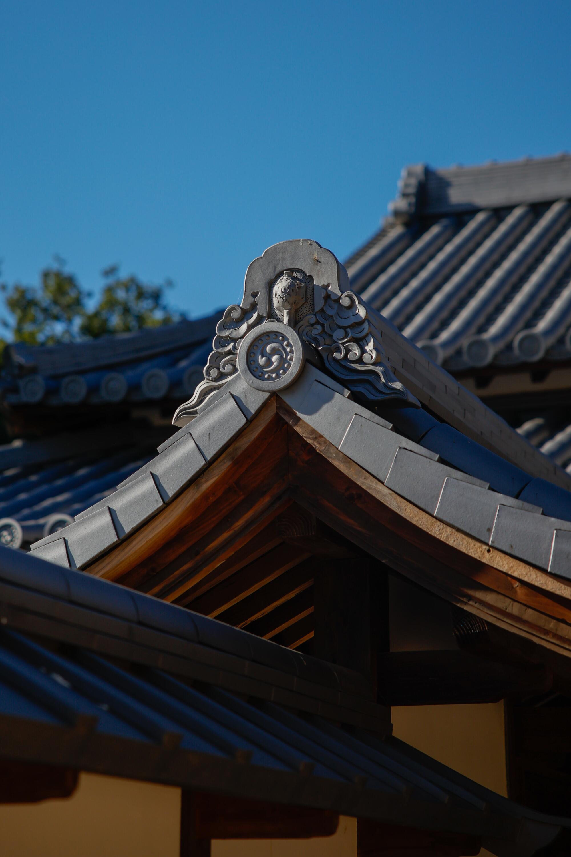 Silver-grey conical ceramic roof tiles on the roof of the Huntington's shōya house with seed decorations.