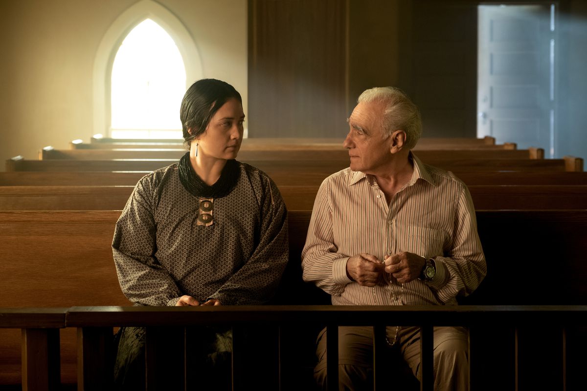 Lily Gladstone og instruktøren Martin Scorsese sidder sammen på en kirkestol i en kirke i et skud bag kulisserne fra Scorsese's Killers of the Flower Moon
