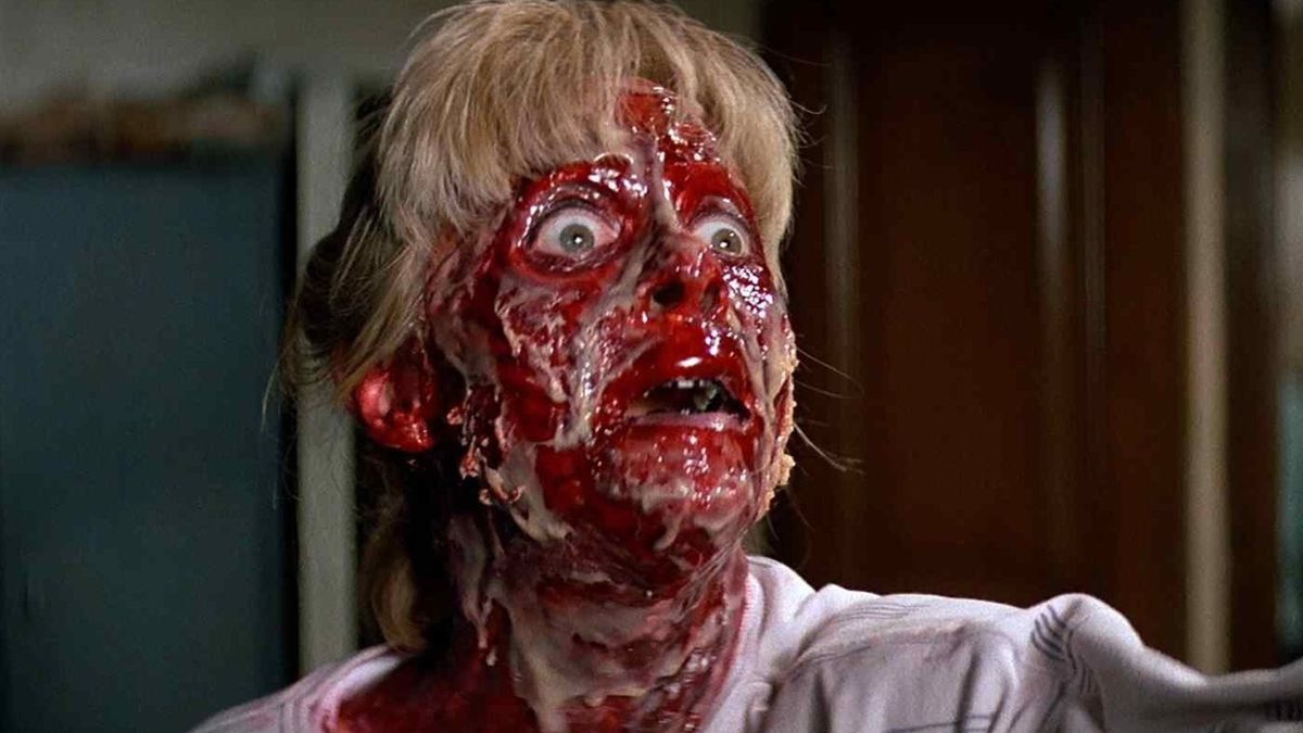 A woman with a skinless face coated in blood and slime recoils in horror in Prince of Darkness.