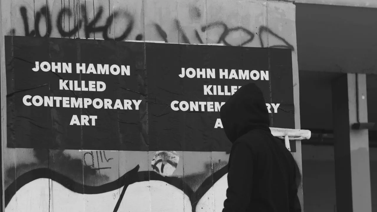 A poster that reads "John Hamon Killed Contemporary Art." 