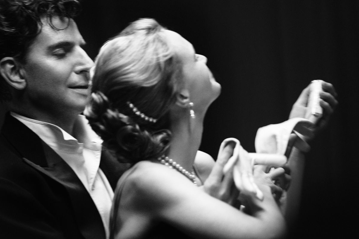 A close-up of Leonard Bernstein (Bradley Cooper) and Felicia Montealegre (Carey Mulligan) in formalwear dancing in a black-and-white scene from Netflix’s Maestro