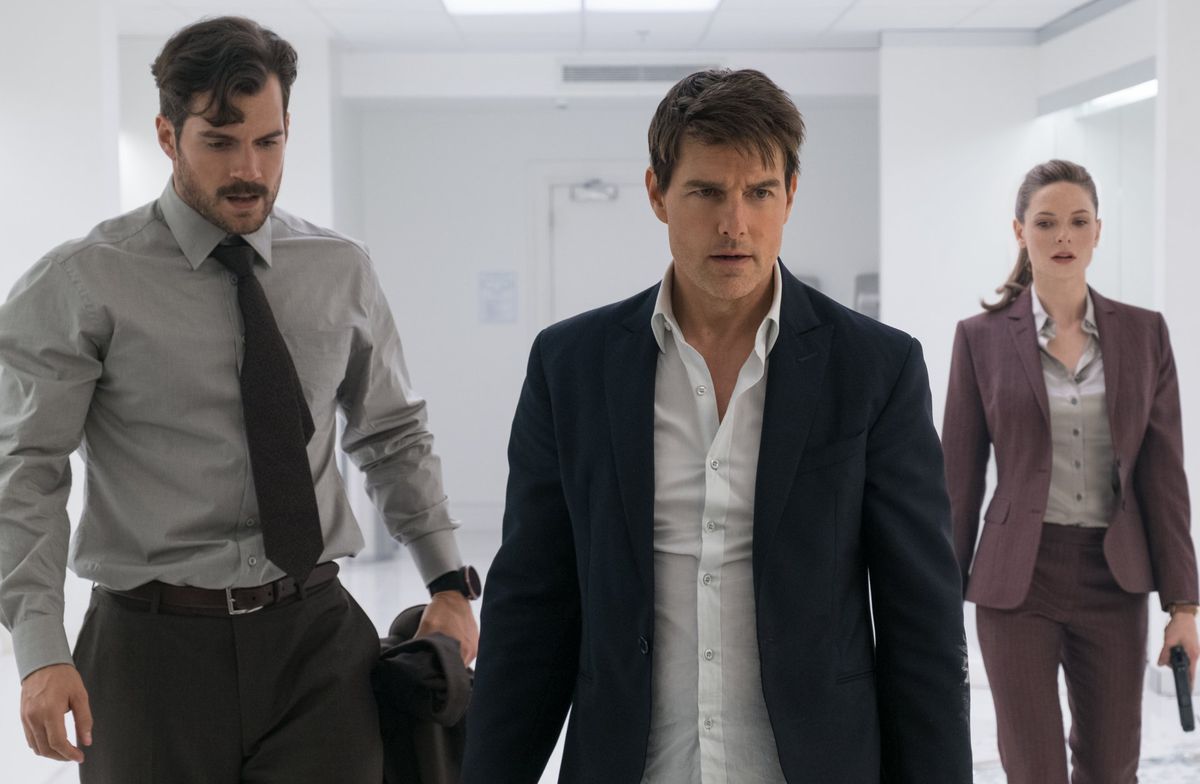Henry Cavill, Tom Cruise e Rebecca Ferguson indossano abiti carini e camminano in una stanza bianca in Mission Impossible Fallout