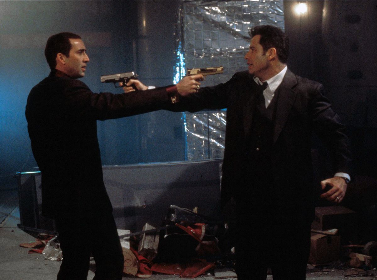 The two men in Face/Off face off, pointing guns at each other.
