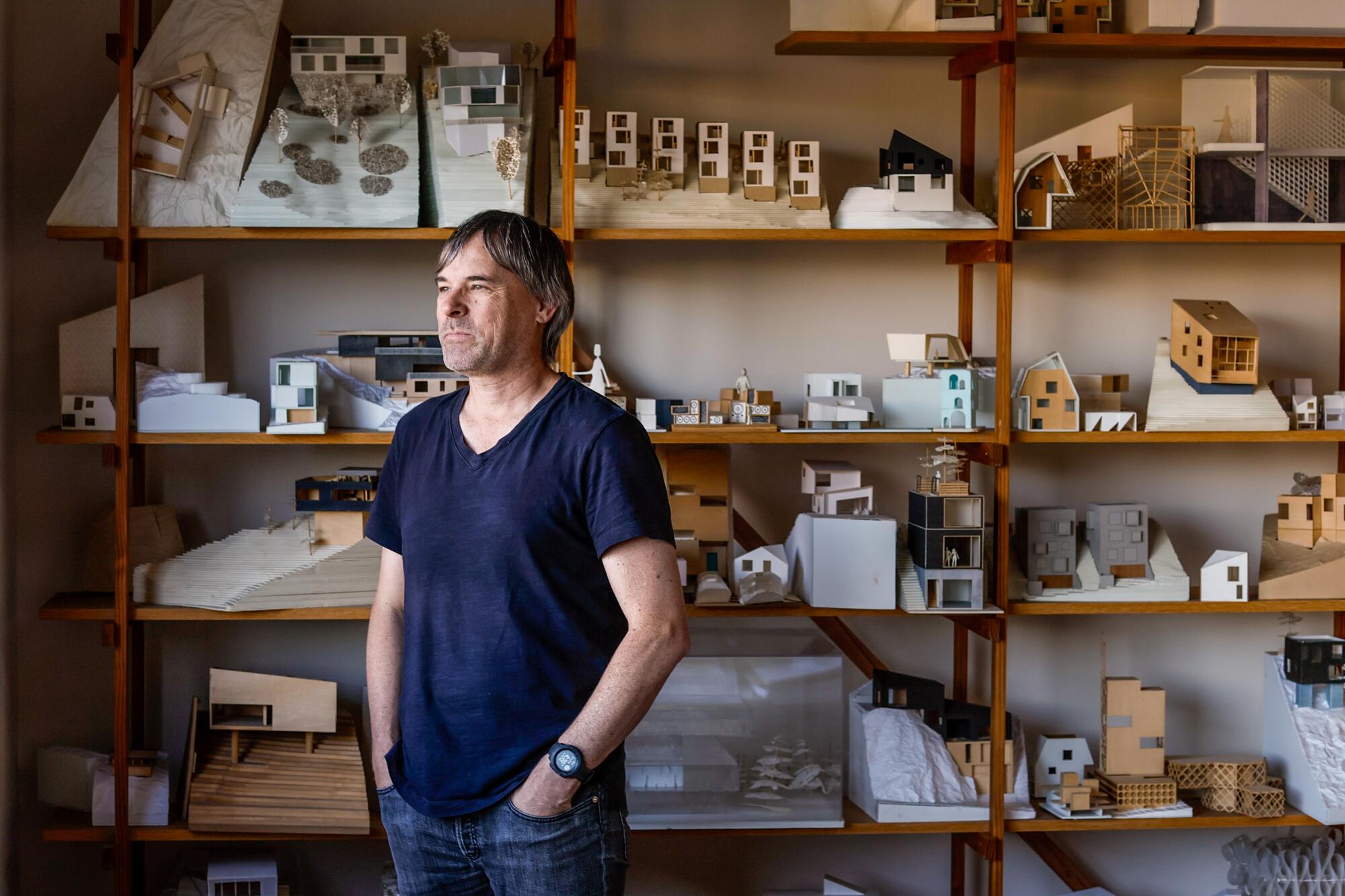 Simon Storey står på hjemmekontoret sitt, der miniatyrmodeller fyller en hylle i veggstørrelse.