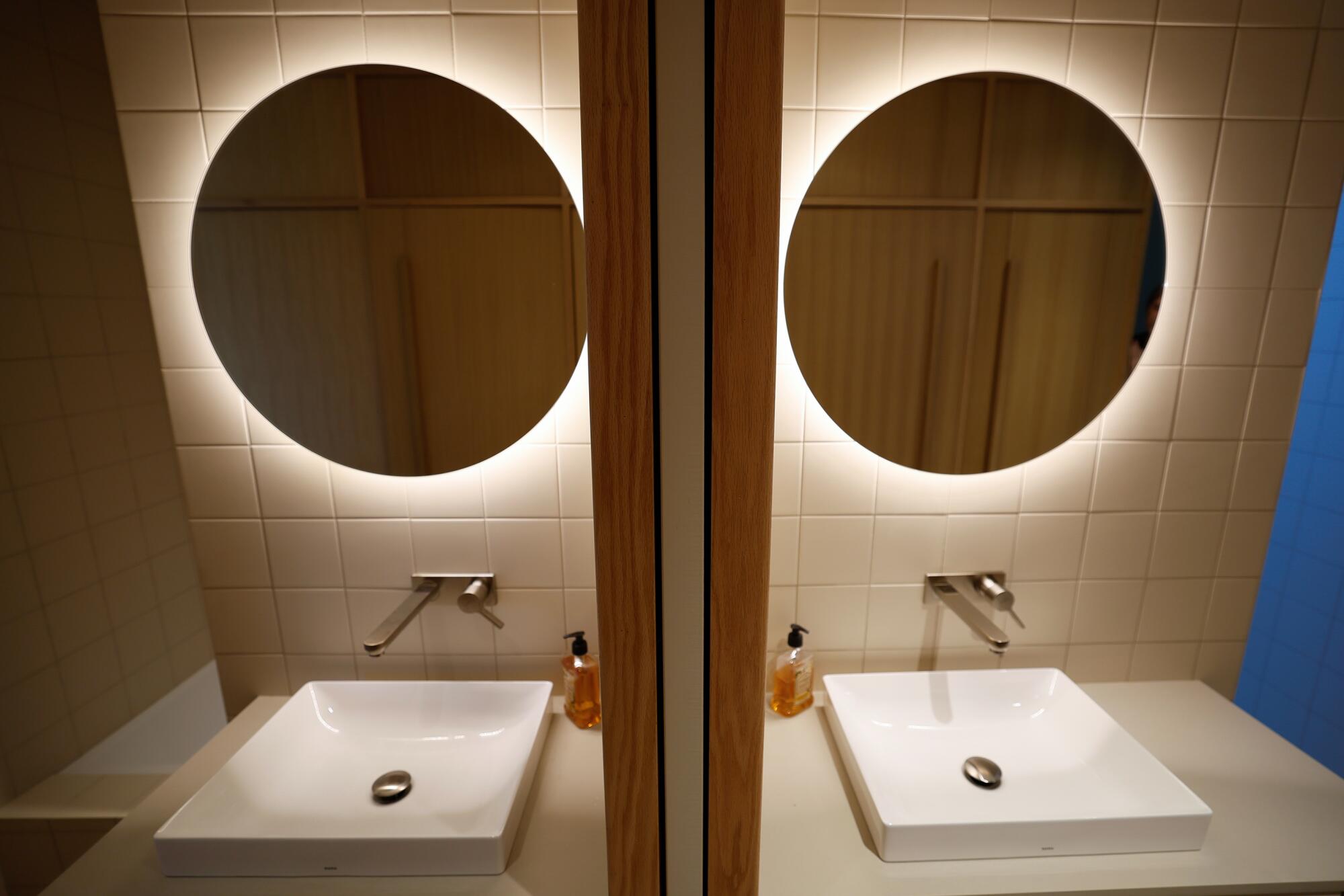 La lumière brille derrière un miroir au-dessus d'un évier, réfléchie dans un miroir.